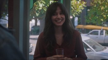 Movie still from “Showing Up” (2022), directed by Kelly Reichardt – A woman smiling while holding a glass of water; Medium shot, Over the shoulder angle