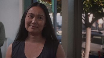 Movie still from “Showing Up” (2022), directed by Kelly Reichardt – A person smiling for a picture; Close Up shot, Over the shoulder angle