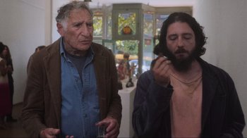 Movie still from “Showing Up” (2022), directed by Kelly Reichardt – Two men standing next to each other in front of a window; Medium shot, Over the shoulder angle