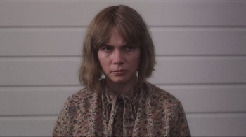 Movie still from “Showing Up” (2022), directed by Kelly Reichardt – A woman in a floral shirt is looking at the camera; Close Up shot, Over the shoulder angle