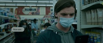 Movie still from “Sick” (2022), directed by John Hyams – A man wearing a face mask while standing in a crowd of people; Close Up shot, Low angle