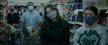 Movie still from “Sick” (2022), directed by John Hyams – A woman wearing a face mask in a grocery store; Medium shot, Low angle