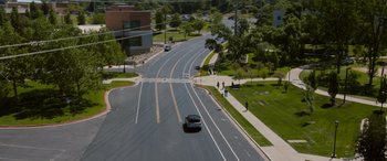 Movie still from “Sick” (2022), directed by John Hyams – A car driving down a street next to a sidewalk; Extreme Wide shot, High angle
