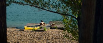 Movie still from “Sick” (2022), directed by John Hyams – A man sitting on a dock next to the water; Extreme Wide shot, High angle