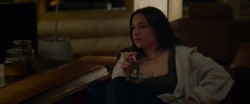 Movie still from “Sick” (2022), directed by John Hyams – A woman sitting on a couch holding a glass of water; Medium shot, High angle