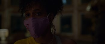 Movie still from “Sick” (2022), directed by John Hyams – A woman wearing a purple face mask with headphones around her neck; Close Up shot, Low angle