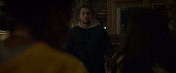 Movie still from “Sick” (2022), directed by John Hyams – A man standing in the dark with his hands in his pockets; Medium shot, Over the shoulder angle