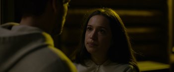 Movie still from “Sick” (2022), directed by John Hyams – A woman sitting next to a man in a room; Close Up shot, Over the shoulder angle