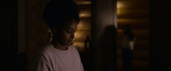 Movie still from “Sick” (2022), directed by John Hyams – A young girl is sitting in a dark room; Close Up shot, Over the shoulder angle