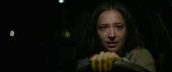 Movie still from “Sick” (2022), directed by John Hyams – A woman holding a banana in front of her face; Close Up shot, Over the shoulder angle