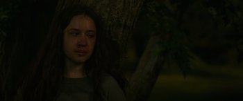 Movie still from “Sick” (2022), directed by John Hyams – A woman sitting in front of a tree with her eyes closed; Close Up shot, Over the shoulder angle