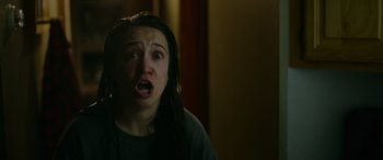 Movie still from “Sick” (2022), directed by John Hyams – A woman with long black hair is looking at the camera; Close Up shot, Over the shoulder angle