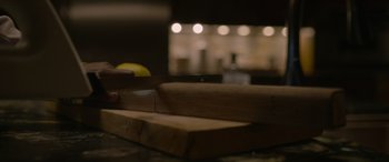 Movie still from “Sick” (2022), directed by John Hyams – A person using a hand saw to cut a piece of wood on a table; Extreme Close Up shot, Low angle