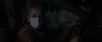 Movie still from “Sick” (2022), directed by John Hyams – A woman wearing a mask sitting in the driver's seat of a car; Close Up shot, Over the shoulder angle
