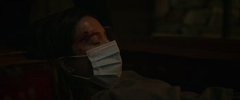 Movie still from “Sick” (2022), directed by John Hyams – A person wearing a face mask with a bandage over their face; Close Up shot, Over the shoulder angle