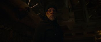Movie still from “Sick” (2022), directed by John Hyams – A man in a black jacket and a black hat; Close Up shot, Low angle
