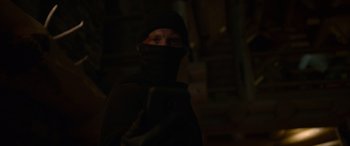 Movie still from “Sick” (2022), directed by John Hyams – A man wearing a black hat and a black scarf; Close Up shot, Low angle