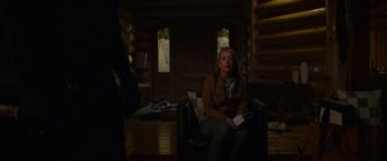 Movie still from “Sick” (2022), directed by John Hyams – A woman sitting on a couch holding a wii controller; Wide shot, Over the shoulder angle