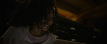 Movie still from “Sick” (2022), directed by John Hyams – A young woman with curly hair is smiling; Close Up shot, Low angle