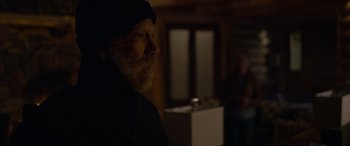 Movie still from “Sick” (2022), directed by John Hyams – A man with a goatee and a black hat is standing in the dark; Medium shot, Over the shoulder angle