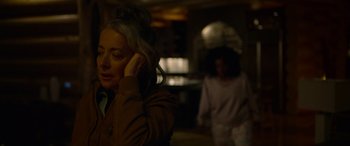 Movie still from “Sick” (2022), directed by John Hyams – A woman with her hand to her ear while another woman walks behind her; Close Up shot, Over the shoulder angle