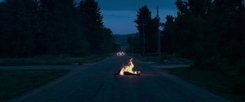 Movie still from “Sick” (2022), directed by John Hyams – A car on fire on the side of the road; Extreme Wide shot, High angle