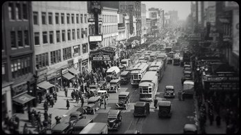 Movie still from “Sidney” (2022), directed by Reginald Hudlin – An old photo of a busy city street filled with cars and buses; Extreme Wide shot, High angle