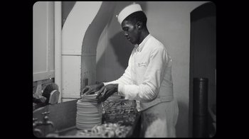 Movie still from “Sidney” (2022), directed by Reginald Hudlin – A black and white photo of a man in a white uniform; Medium shot, High angle