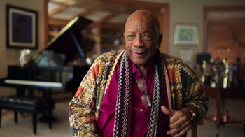 Movie still from “Sidney” (2022), directed by Reginald Hudlin – An older man wearing a multicolored jacket; Medium shot, Overhead angle
