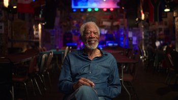 Movie still from “Sidney” (2022), directed by Reginald Hudlin – An older man sitting in a chair in a room; Medium shot, Low angle