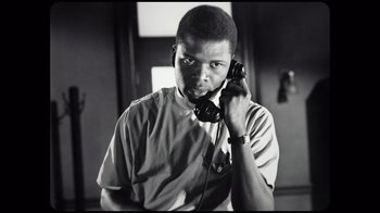 Movie still from “Sidney” (2022), directed by Reginald Hudlin – A black and white photo of a man holding a phone to his ear; Close Up shot, Low angle
