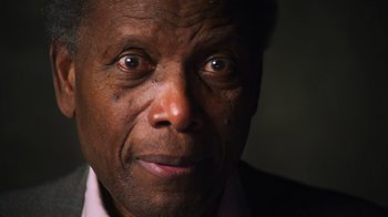 Movie still from “Sidney” (2022), directed by Reginald Hudlin – An older man with a black shirt on looking at the camera; Close Up shot, Low angle