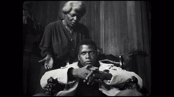 Movie still from “Sidney” (2022), directed by Reginald Hudlin – An older man getting his hair combed by an older woman; Medium shot, Low angle