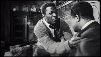 Movie still from “Sidney” (2022), directed by Reginald Hudlin – A black and white photo of a man in a room; Medium shot, Over the shoulder angle