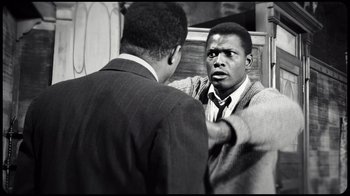 Movie still from “Sidney” (2022), directed by Reginald Hudlin – A black and white photo of a man talking to another man in a suit; Medium shot, Over the shoulder angle