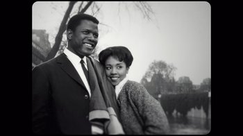 Movie still from “Sidney” (2022), directed by Reginald Hudlin – An older man standing next to an older woman in a park; Medium shot, Low angle