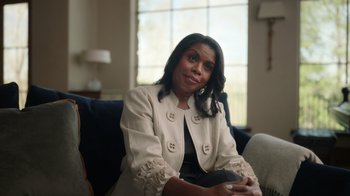 Movie still from “Sidney” (2022), directed by Reginald Hudlin – A woman sitting on a couch in a room; Medium shot, Over the shoulder angle