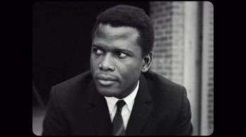 Movie still from “Sidney” (2022), directed by Reginald Hudlin – A black and white photo of a man wearing a suit and tie; Close Up shot, Low angle