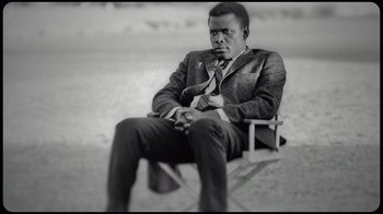 Movie still from “Sidney” (2022), directed by Reginald Hudlin – A black and white photo of a man sitting on a bench; Medium shot, High angle