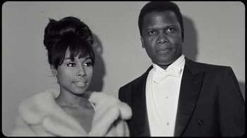 Movie still from “Sidney” (2022), directed by Reginald Hudlin – A man and a woman posing for a picture; Close Up shot, Low angle