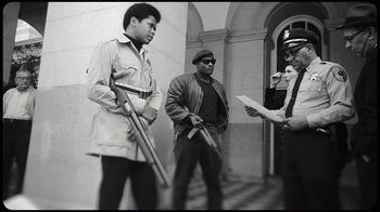 Movie still from “Sidney” (2022), directed by Reginald Hudlin – A group of men standing next to each other holding guns; Medium shot, Low angle