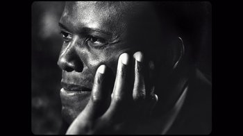 Movie still from “Sidney” (2022), directed by Reginald Hudlin – A black - and - white photo of a man holding a cell phone to his ear; Close Up shot, Low angle