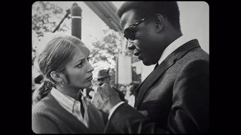 Movie still from “Sidney” (2022), directed by Reginald Hudlin – A man and a woman standing next to each other on the street; Close Up shot, Low angle