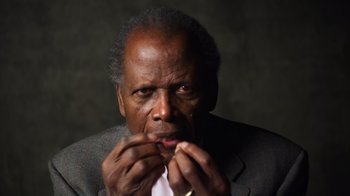 Movie still from “Sidney” (2022), directed by Reginald Hudlin – An older man in a gray suit and a white shirt; Close Up shot, Low angle