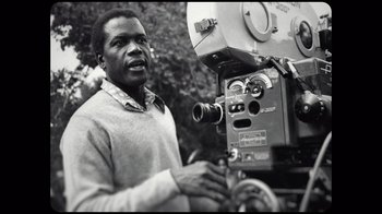 Movie still from “Sidney” (2022), directed by Reginald Hudlin – A black and white photo of a man standing next to a camera; Close Up shot, Low angle