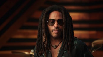 Movie still from “Sidney” (2022), directed by Reginald Hudlin – A person with dreadlocks wearing sunglasses; Close Up shot, Low angle
