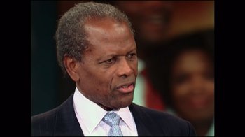 Movie still from “Sidney” (2022), directed by Reginald Hudlin – An older man in a suit and tie looking to his left; Close Up shot, Over the shoulder angle