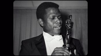 Movie still from “Sidney” (2022), directed by Reginald Hudlin – A black and white photo of a man holding an award; Close Up shot, Low angle