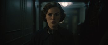 A woman in a black jacket standing in a dark room