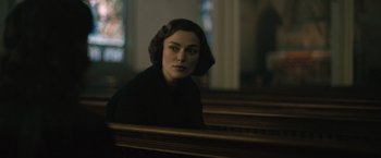 A woman sitting in a pew in front of a stained glass window